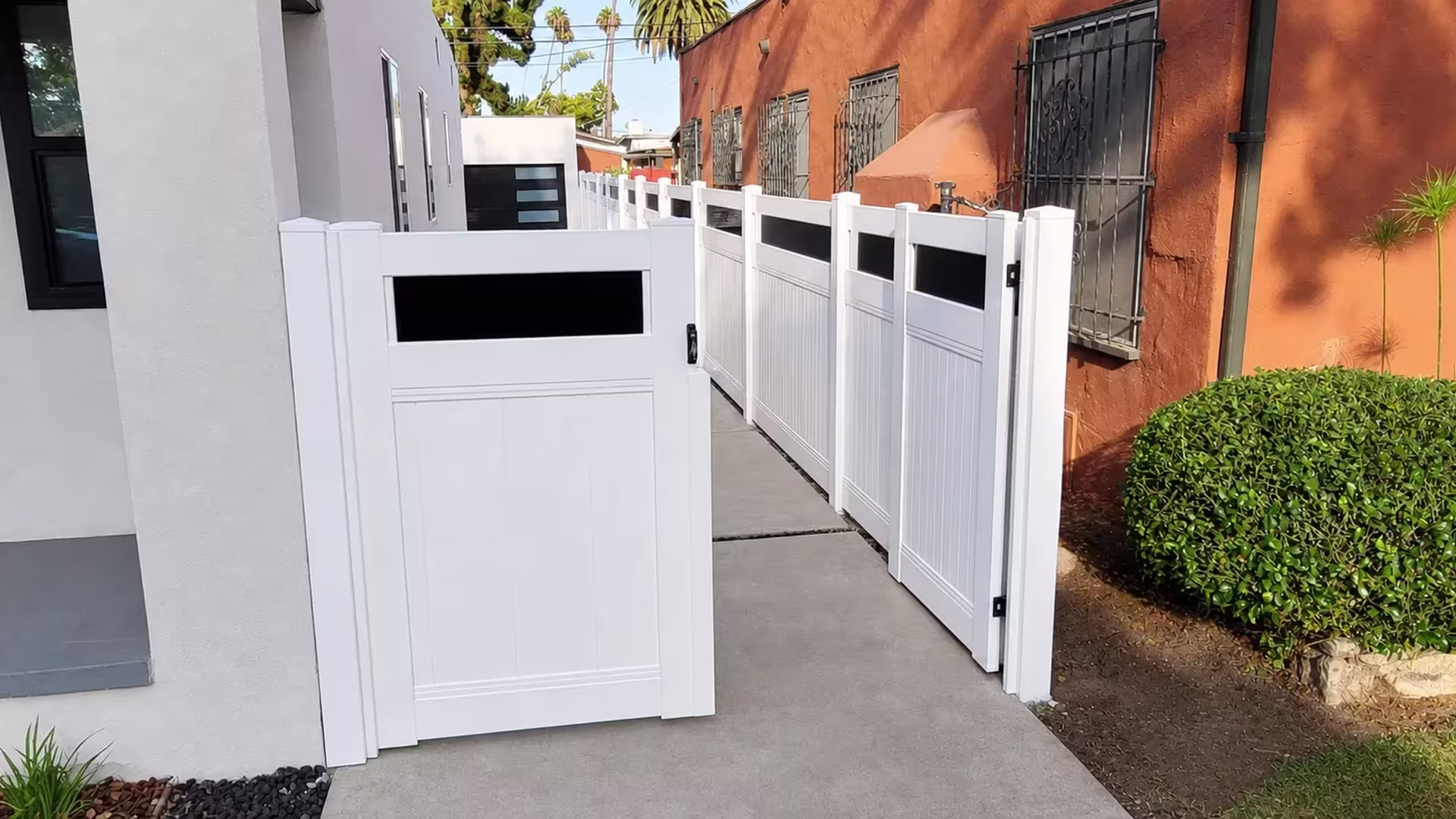 A single gate leaf sits ajar in this White vinyl privacy fence with acrylic positioned within a narrow side passage
