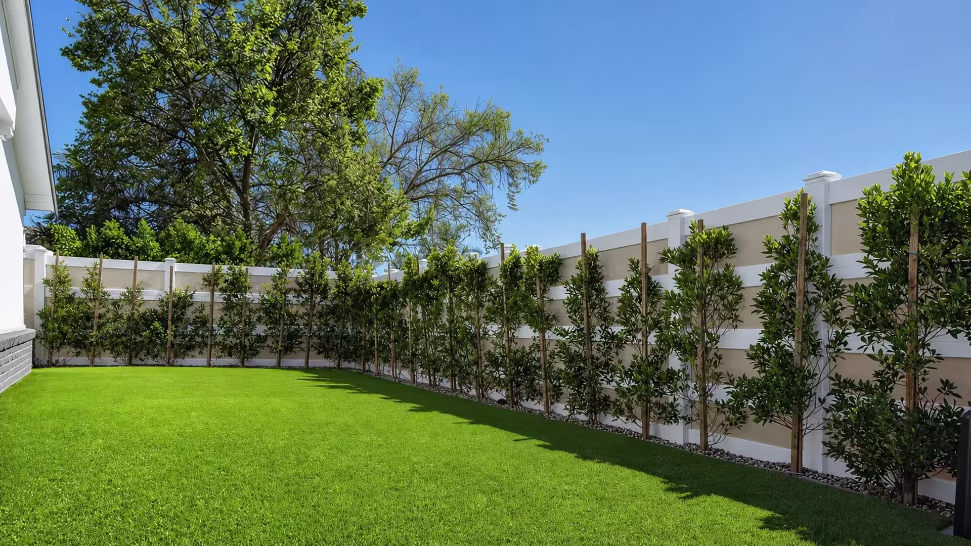 Staked young trees line this White vinyl privacy fence with amber toned acrylic sections at the rear corner