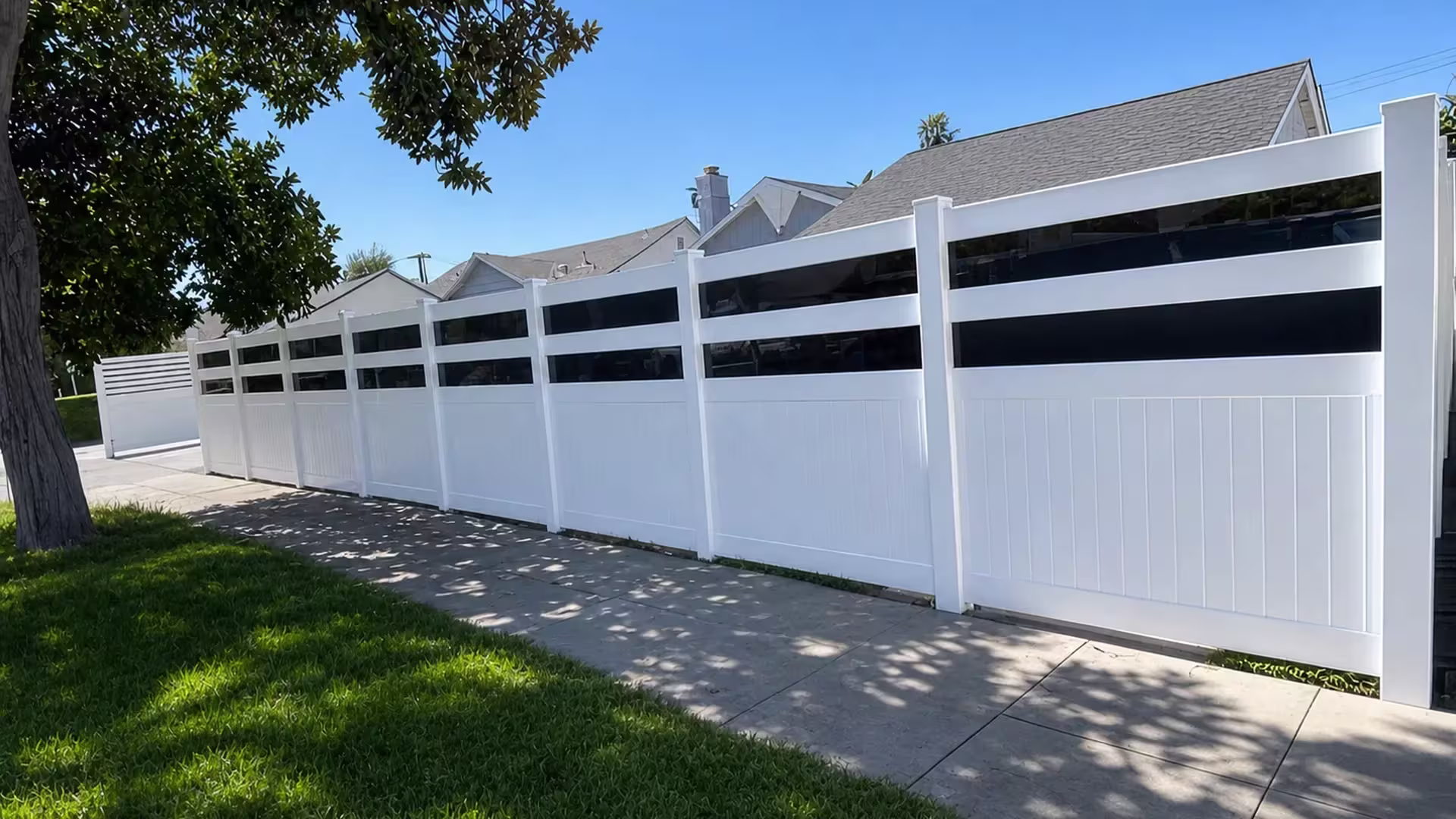 Sidewalk runs alongside this White vinyl privacy fence with smoke tinted acrylic bands set on a diagonal line