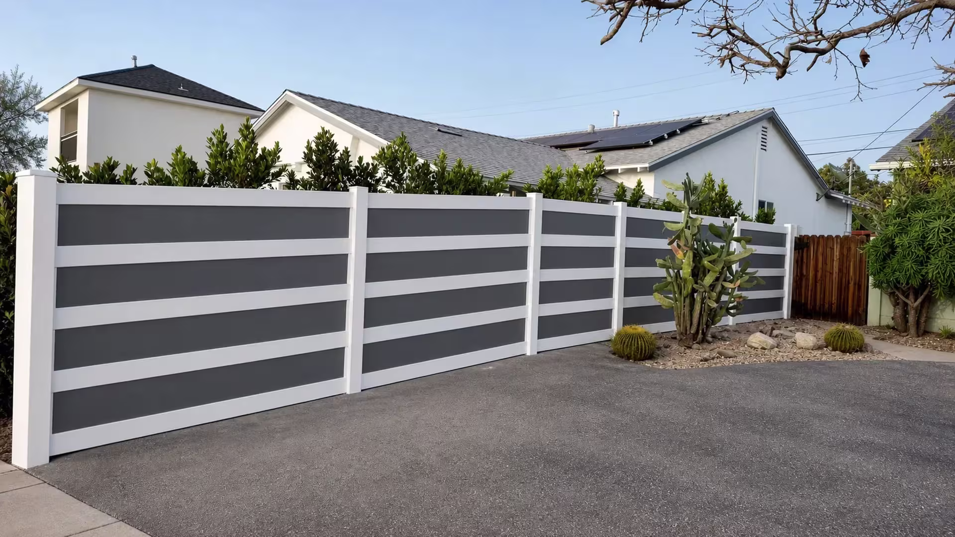 Existing wood fence borders this White vinyl privacy fence with smoky gray acrylic bands near a cactus garden