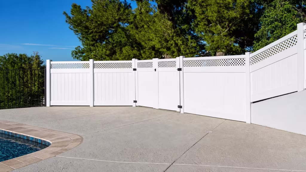 Two gate leaves meet at the center of a lattice banded White vinyl privacy fence enclosing a pool area