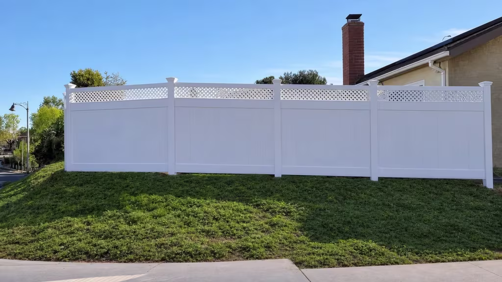 A corner streetlamp and brick house edge frame a White vinyl lattice topped privacy fence run