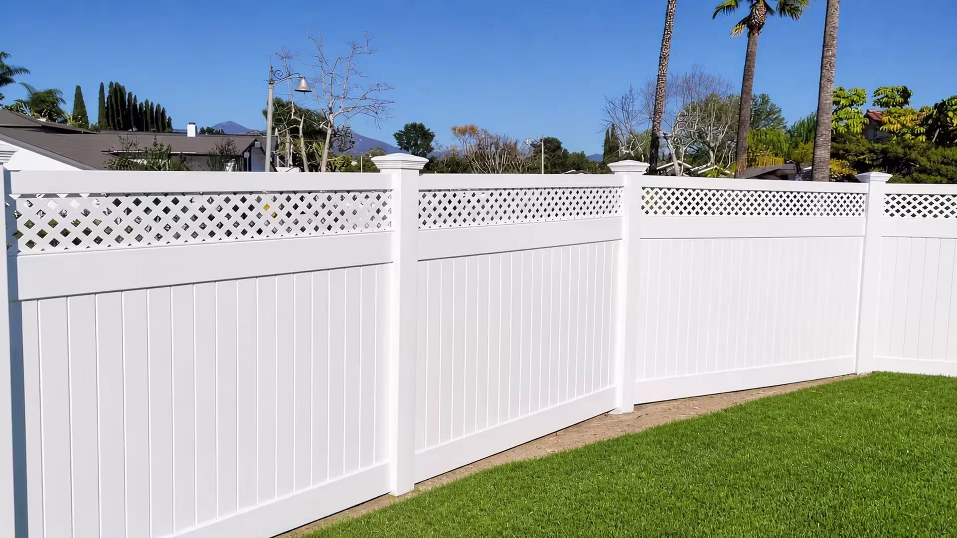 Distant mountains rise beyond a White vinyl privacy fence turning across the side yard