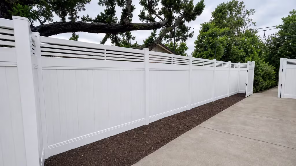 A large foreground corner post anchors this newly installed White vinyl fence with a picket top