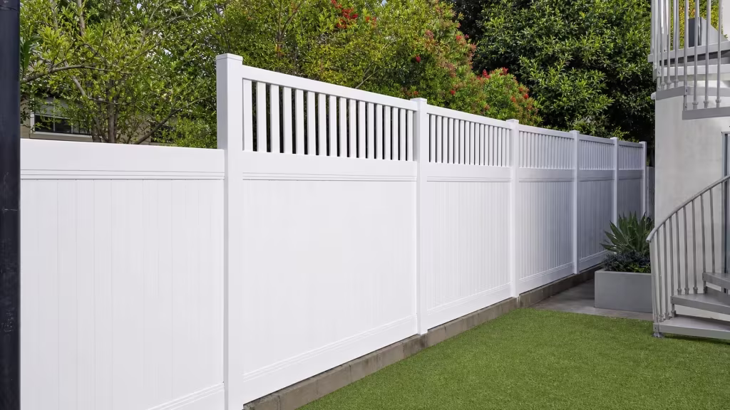 Six square posts carry this White vinyl fence with a picket top along a masonry curb past exterior stairs