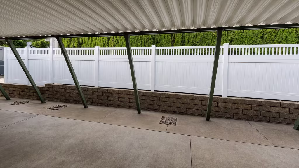 Repeating rectangular bays give this White vinyl fence with a picket top a steady rhythm along the property line
