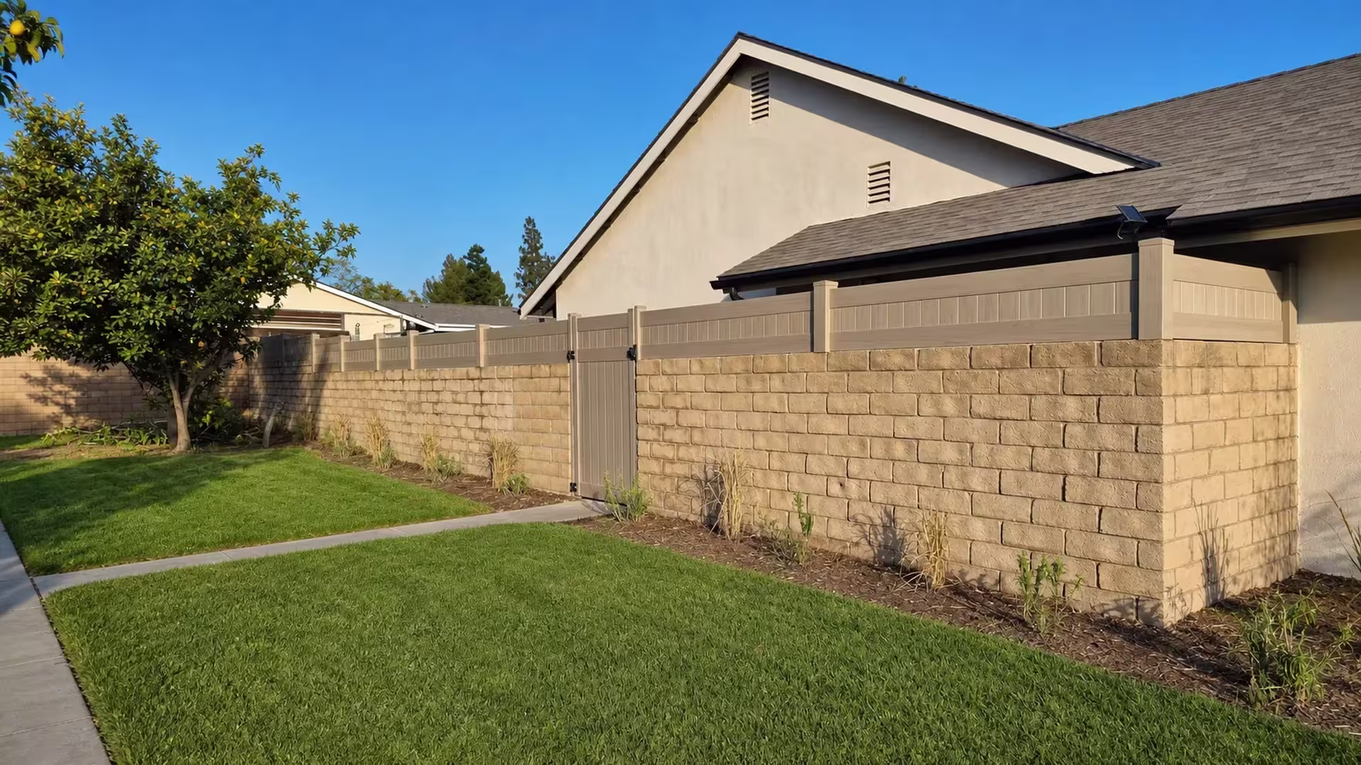 Mesquite vinyl wall topper runs across the yard past a mature citrus tree to a corner return beside the house