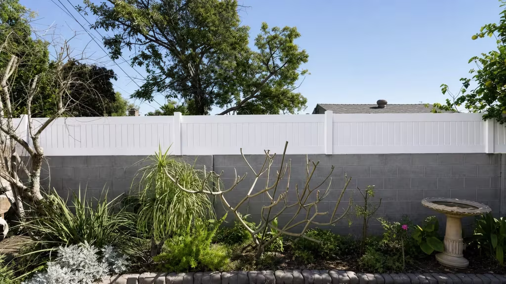 White vinyl topper spans a gray block wall beneath overhead utility lines and a neighboring roofline