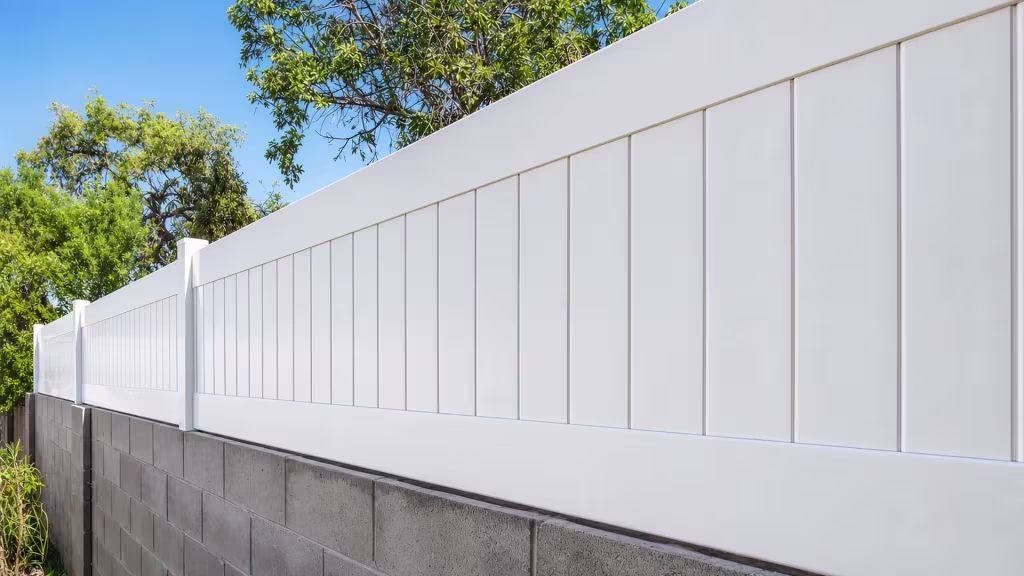 Continuous White vinyl wall topper follows a mortared block wall lined with mature tree trunks and foliage