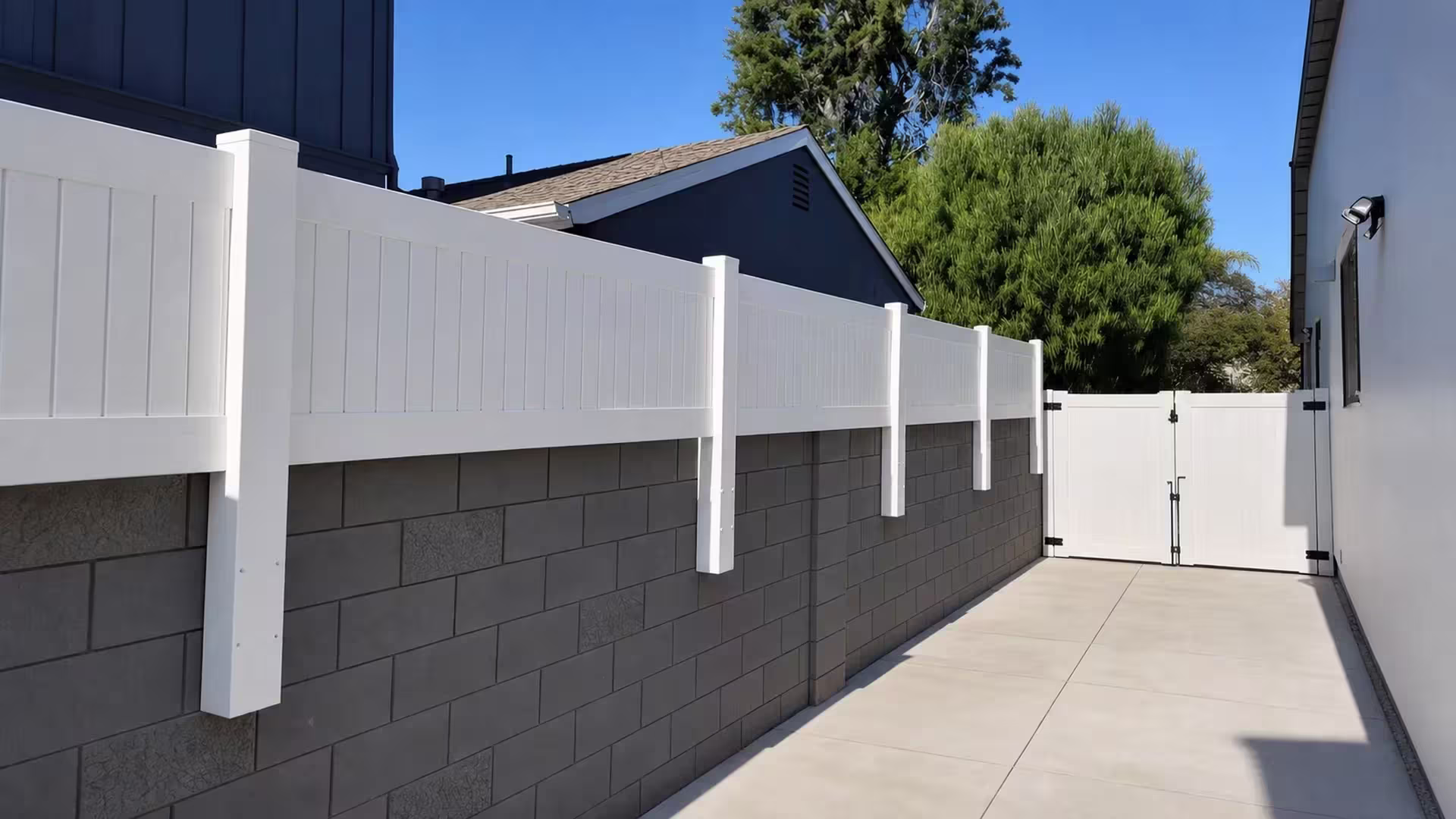 Long White vinyl wall topper extends toward an existing gate along a dark block wall