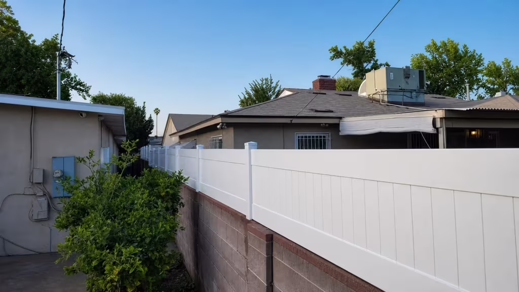 White vinyl wall topper recedes along a brown block wall below a rooftop chimney and HVAC unit