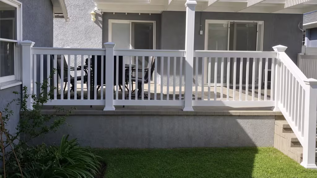 White vinyl deck railing spans an elevated patio with four square posts set on a masonry base