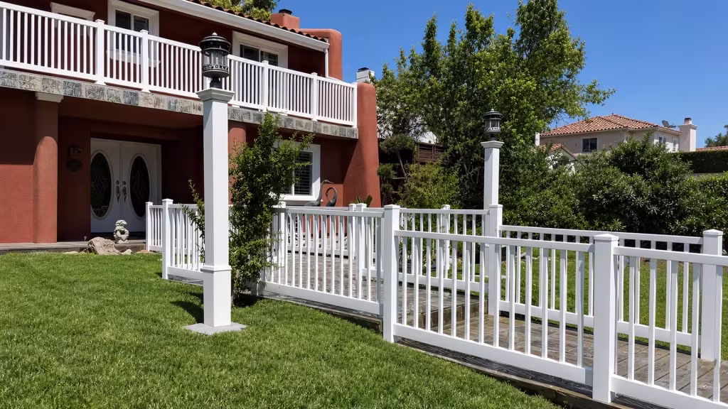 White vinyl picket railing running from a terracotta stucco balcony down to a wooden walkway below