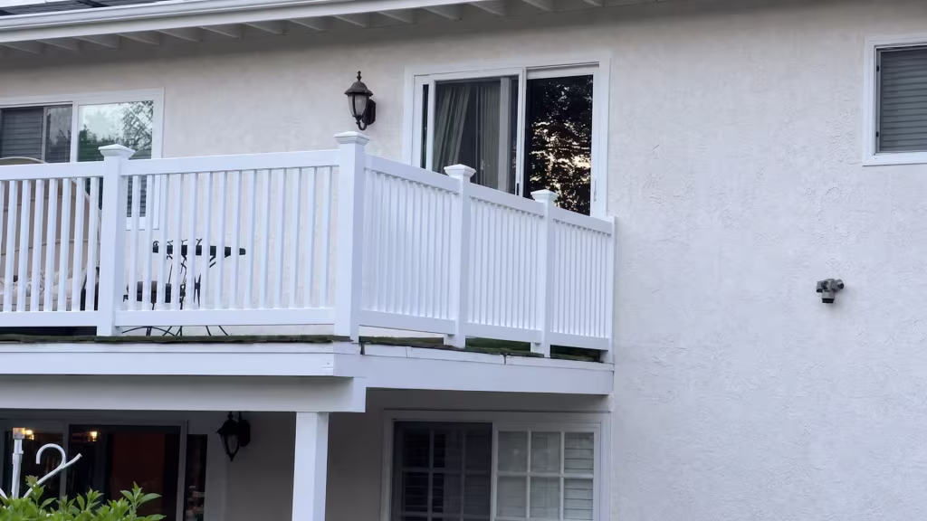 White vinyl deck and stair railing descends from an elevated deck on a stucco residence