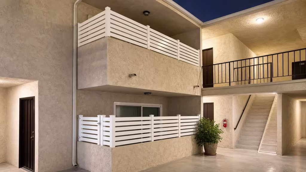 White vinyl open slat balcony railing turns a corner post near a wall mounted fire extinguisher