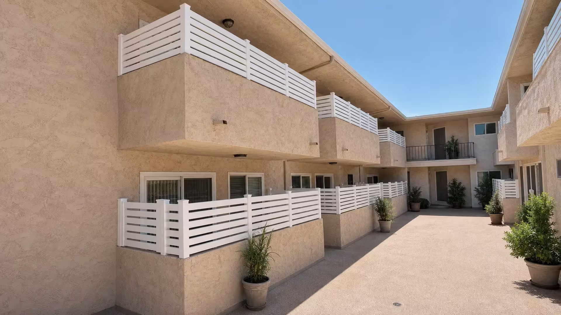 Balcony and patio walls throughout a two story courtyard carry White vinyl open slat wall topper railing