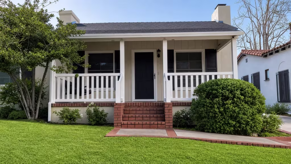 White vinyl porch railing runs on both sides of a centered brick staircase at a one story house