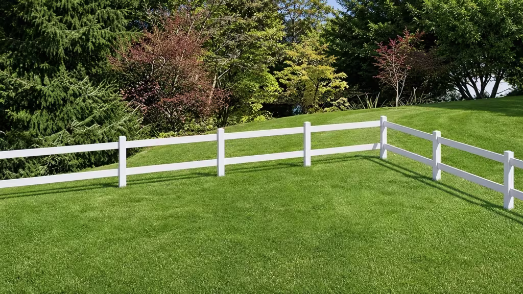 Two-rail White vinyl ranch fencing crosses a rolling lawn among scattered trees and shrubs