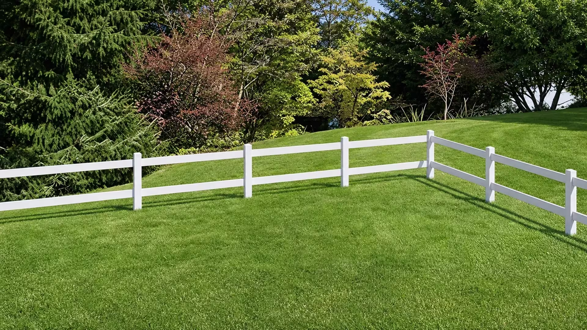 Two-rail White vinyl ranch fencing crosses a rolling lawn among scattered trees and shrubs