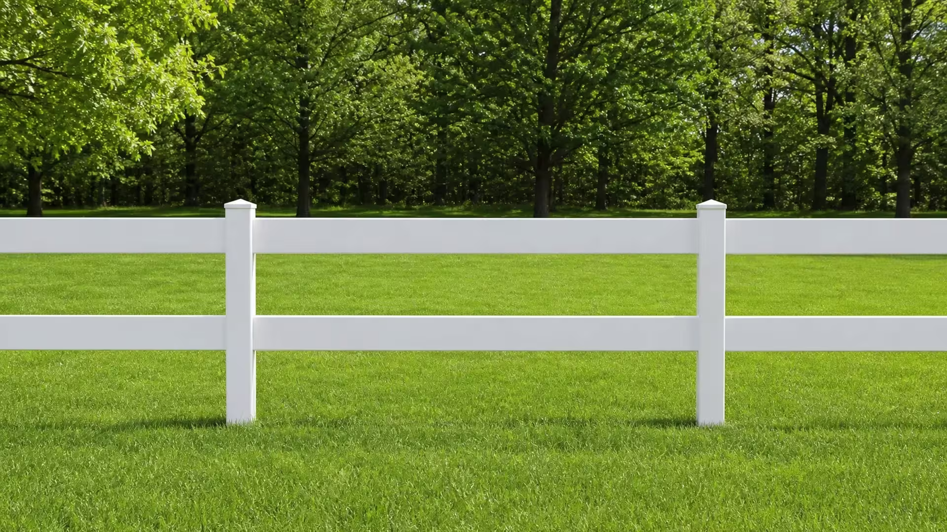 White vinyl two-rail ranch fencing forms one complete bay bounded by pyramid-capped posts