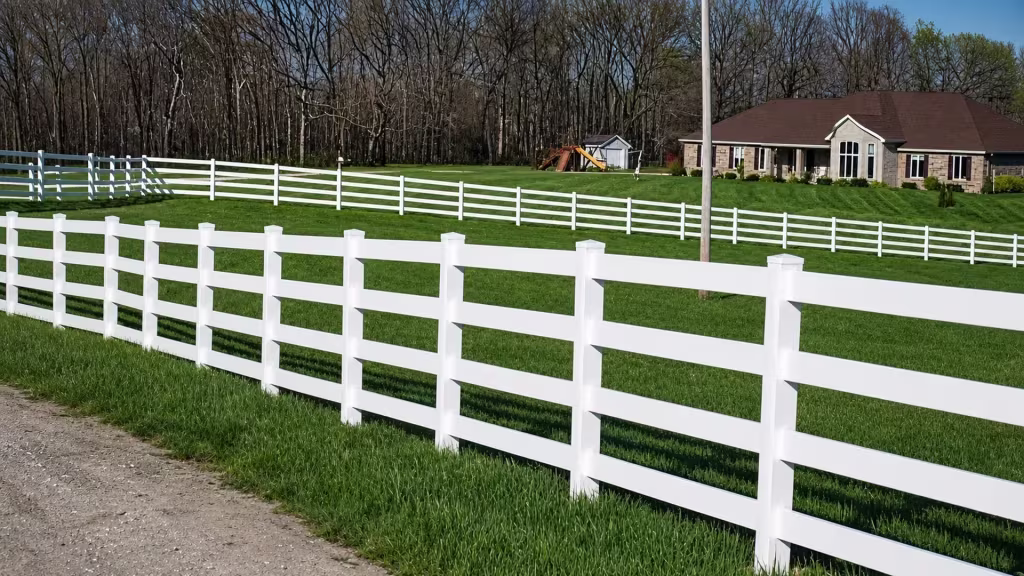 Eight square posts support this White vinyl four rail fence as it crosses a large lawn near sheds and a pole