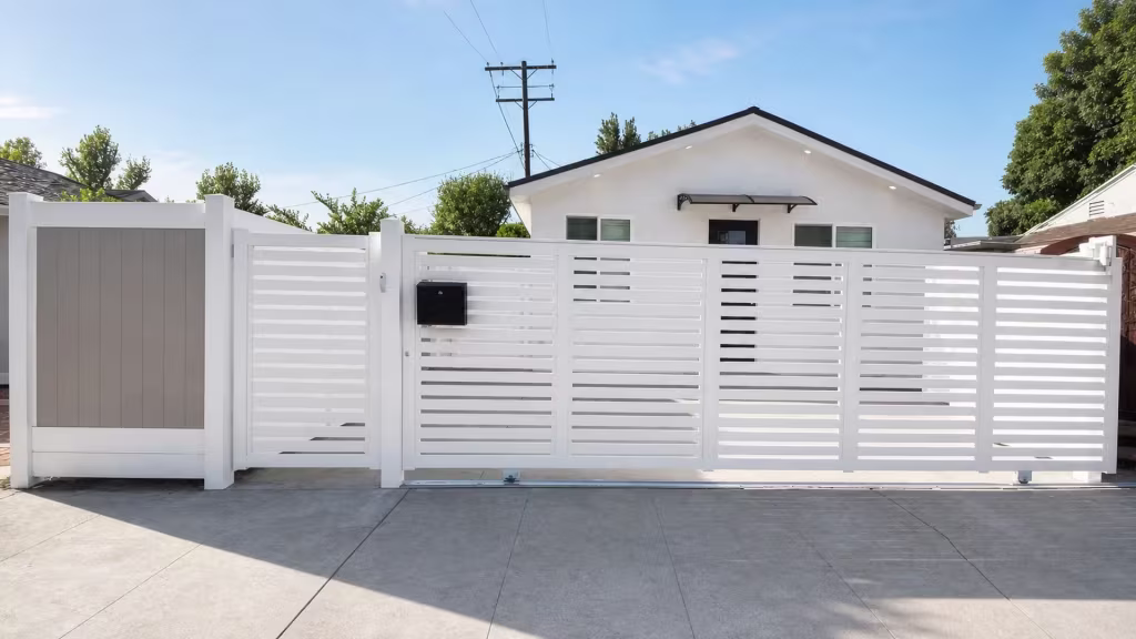 A rolling White vinyl gate opens beside a fixed warm-gray tongue-and-groove panel and a narrower slatted section