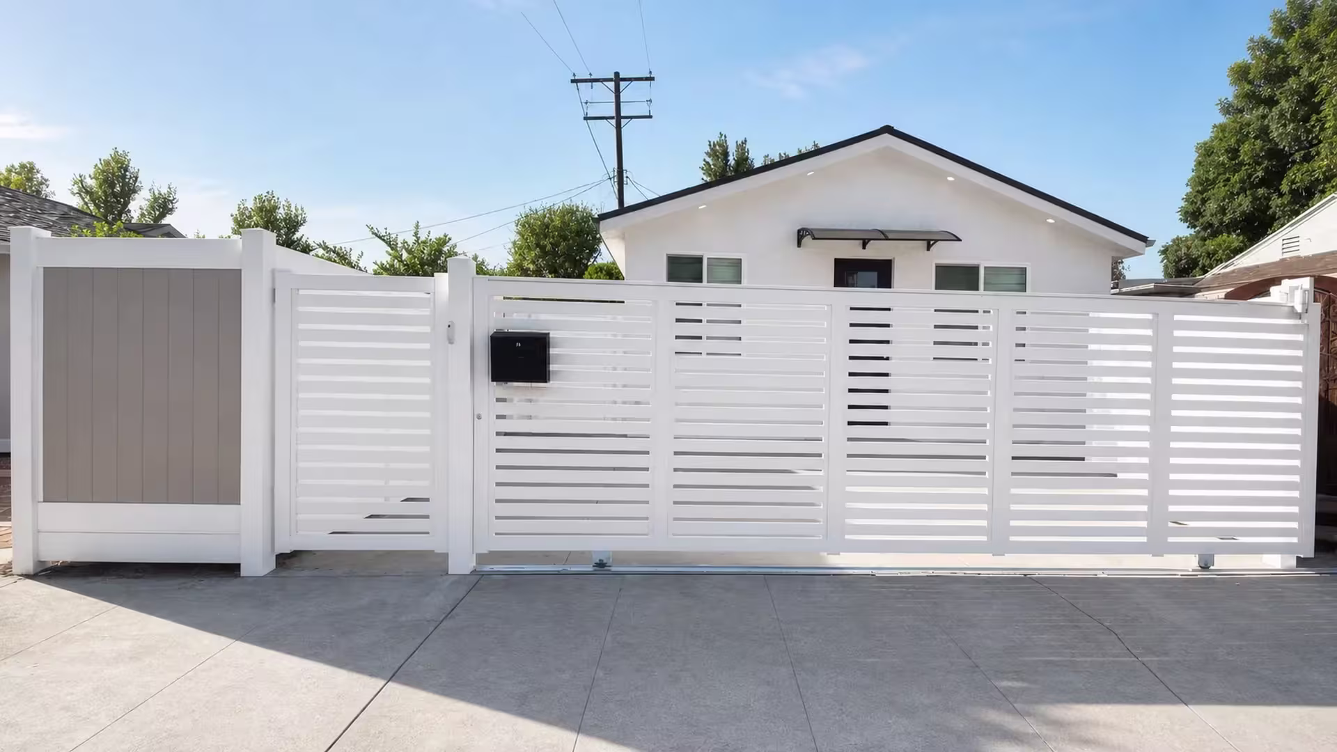 A rolling White vinyl gate opens beside a fixed warm-gray tongue-and-groove panel and a narrower slatted section