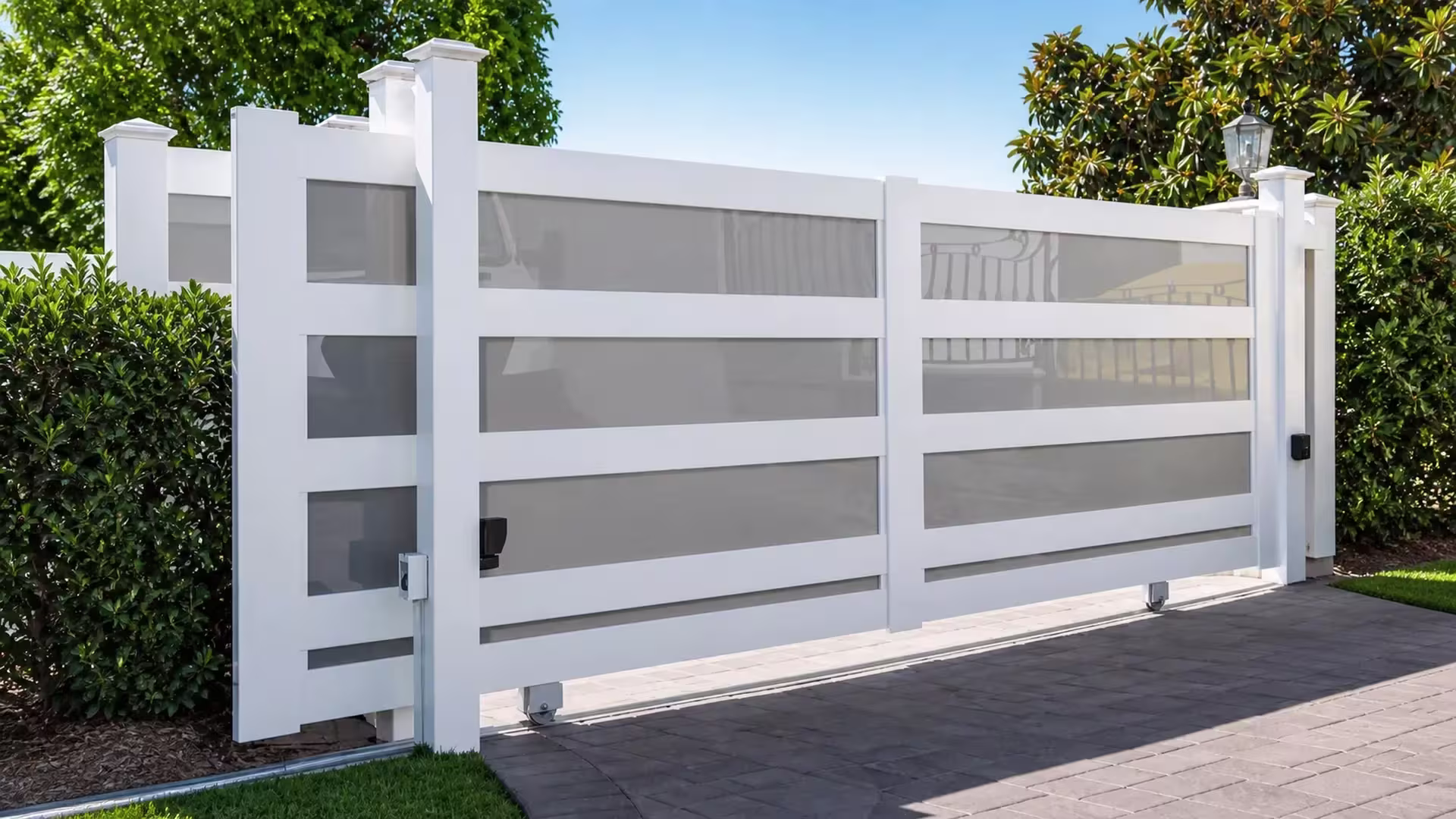 Three stacked acrylic rows fill this White vinyl rolling gate, its leaf sliding along a lawn-edged paved driveway