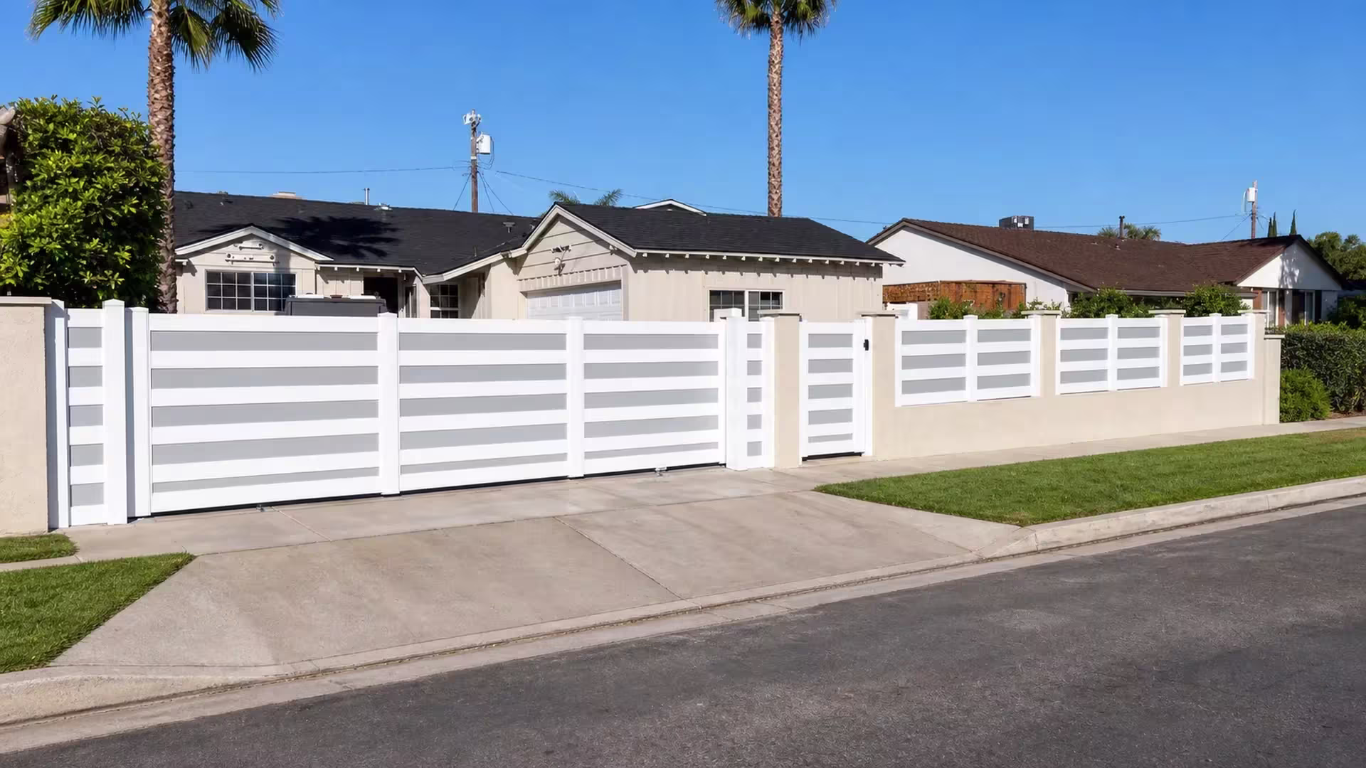 Four stacked acrylic bands span three bays of this White vinyl rolling gate, set beside a cream masonry wall topper run