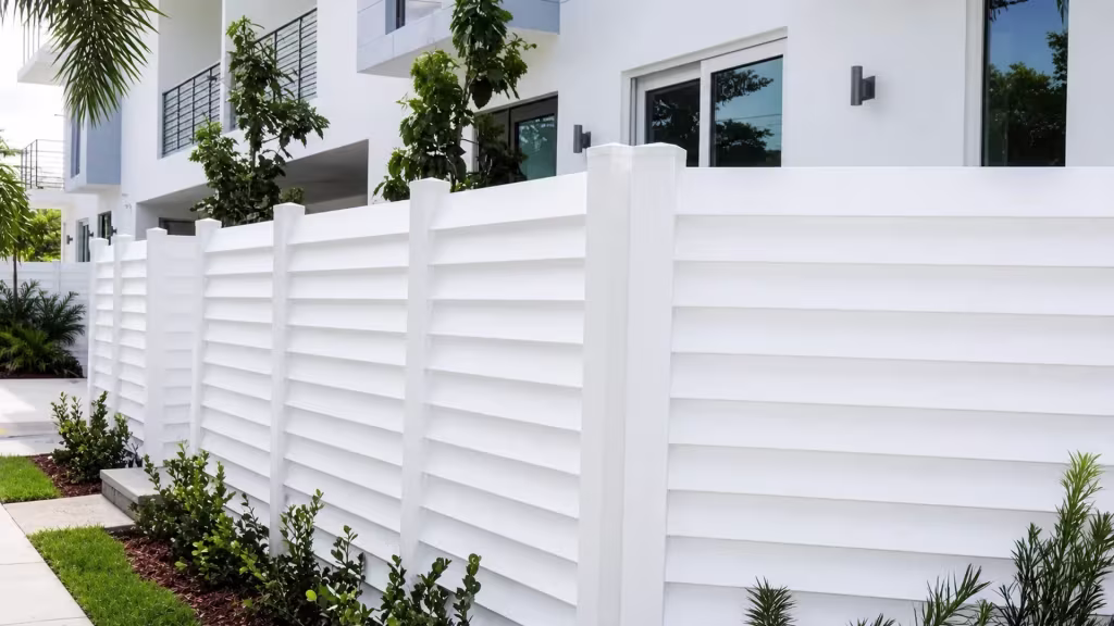 This horizontal-louver semi-privacy fence in White vinyl runs the length of a multi-story residence wall