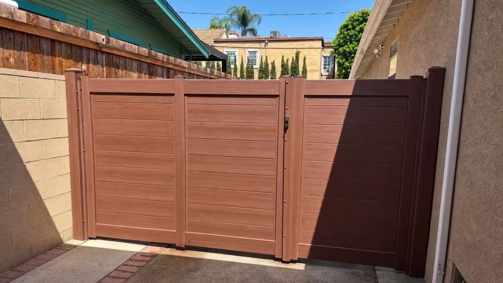 A brick-edged driveway lined with palm trees carries a Brazilian Blend vinyl gate at the property line