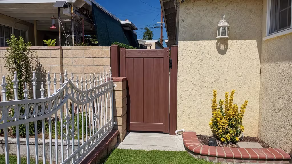 Brazilian Blend vinyl side gate installed beside a curved brick planter and a tan block wall