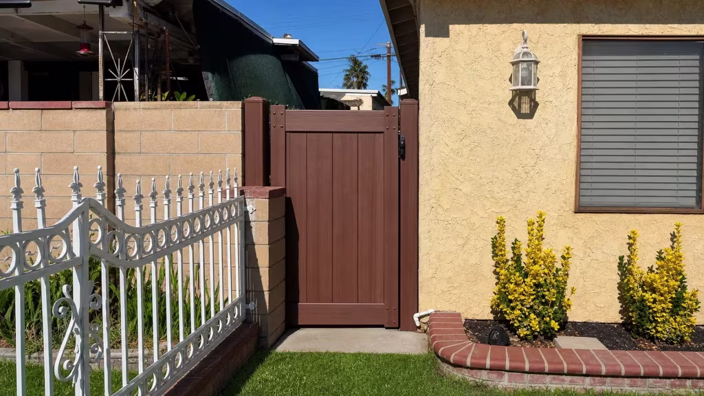Brazilian Blend vinyl side gate positioned next to a white metal fence and a curved brick planting bed
