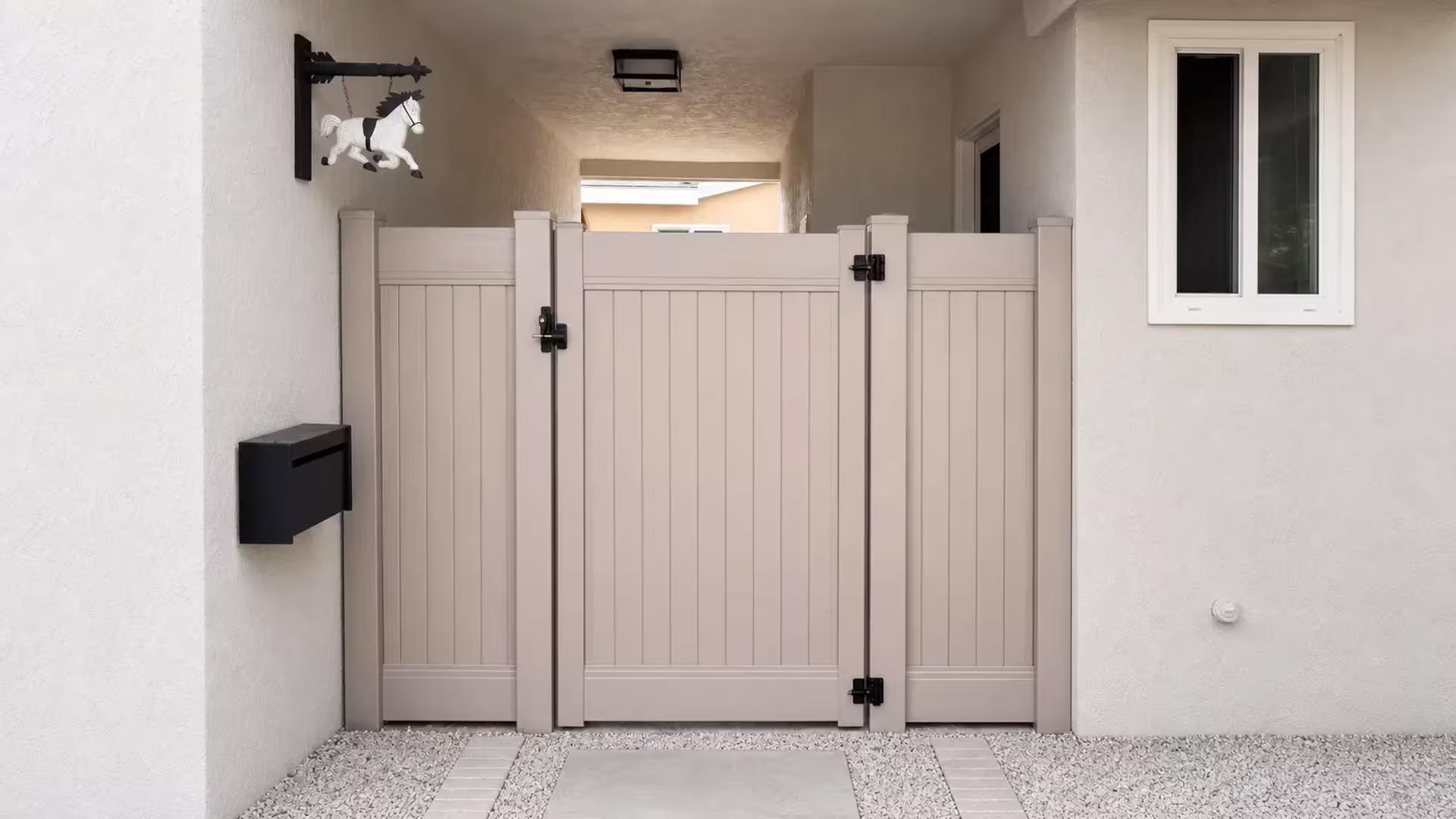 Clay vinyl side gate set across a covered stucco passage with a gravel and paver floor