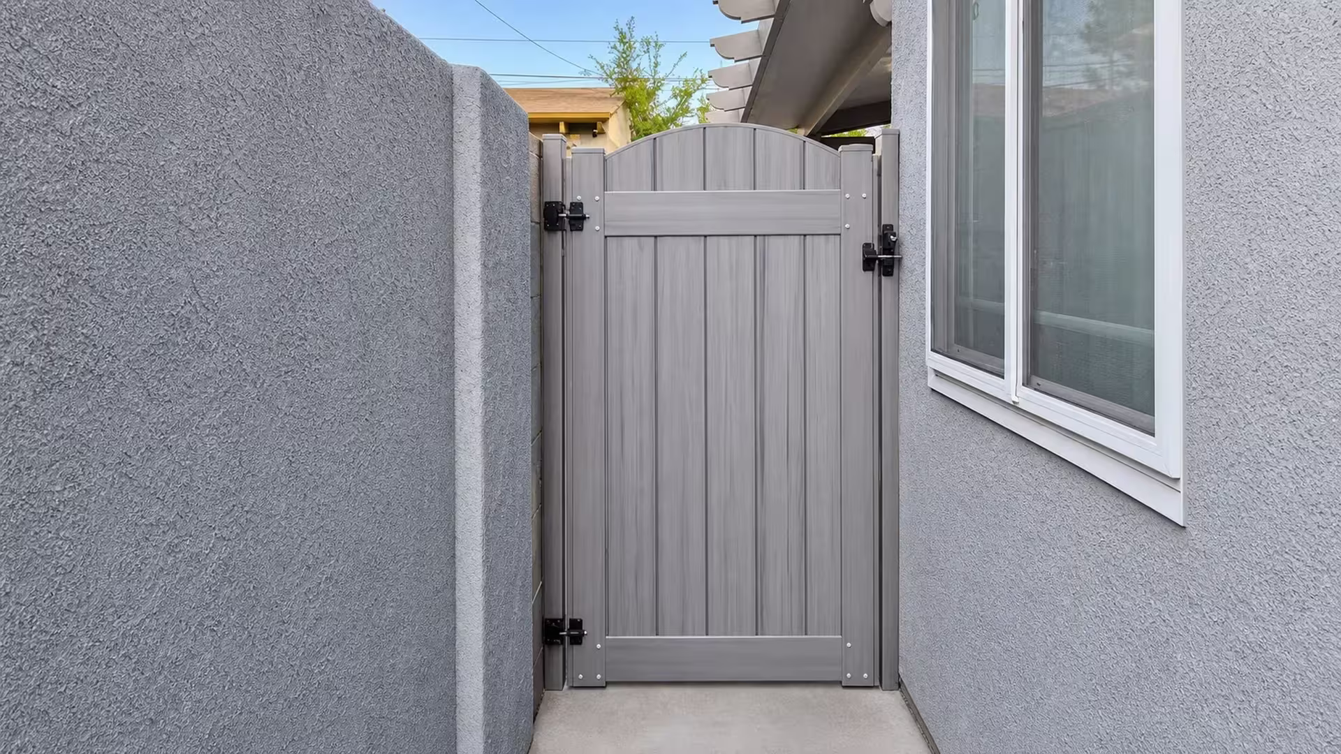 Coastal Cedar vinyl side gate fitted into a narrow passage between a masonry wall and a stucco house