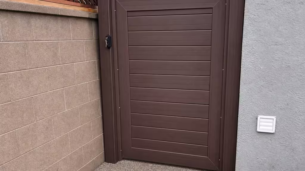 Dark Walnut vinyl side gate installed beside a masonry wall topped with diagonal wood lattice