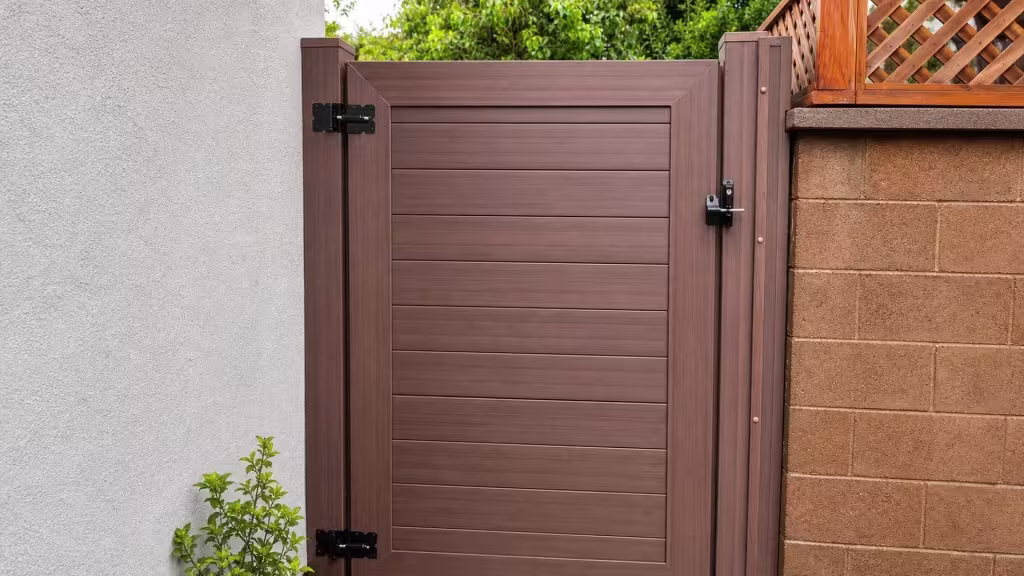 A masonry pillar and an upper wood fence line flank this Dark Walnut vinyl side gate