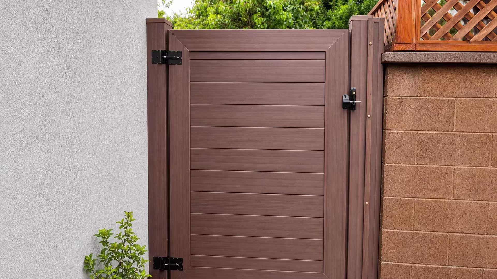 A masonry pillar and an upper wood fence line flank this Dark Walnut vinyl side gate