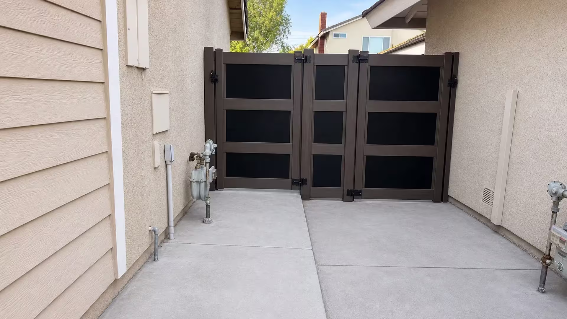 Two stucco buildings flank a Dark Walnut vinyl gate fitted with translucent acrylic infill panels