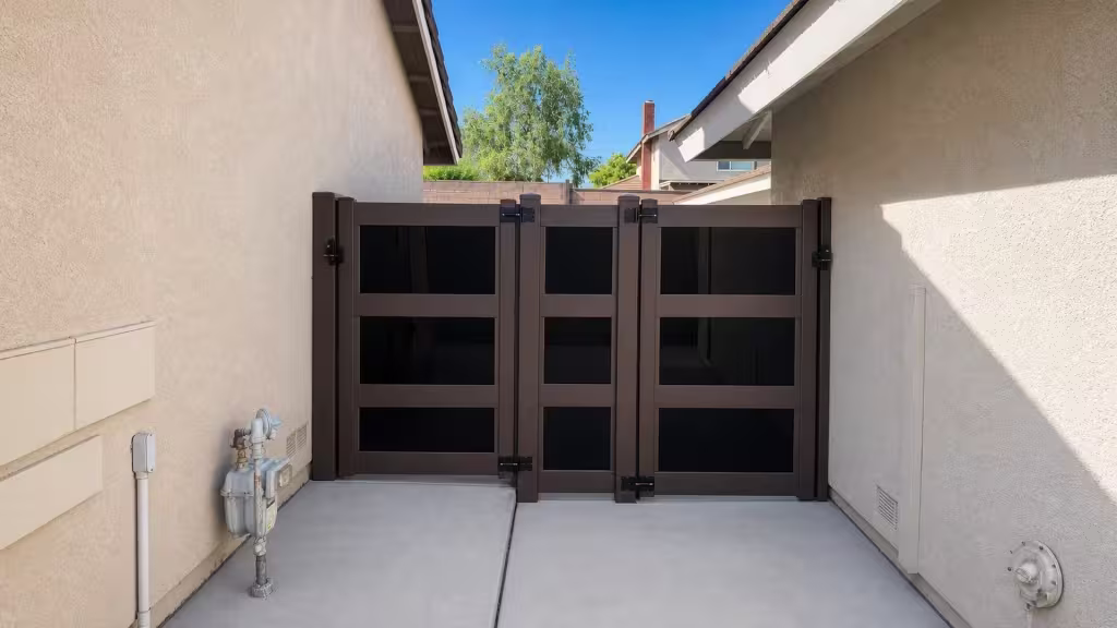 A concrete passage between two stucco buildings is closed by this Dark Walnut vinyl side gate