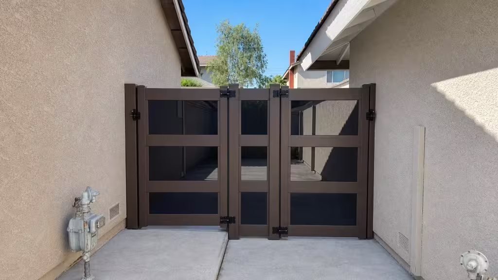 Three square capped posts carry a Dark Walnut vinyl gate assembly along a concrete passage