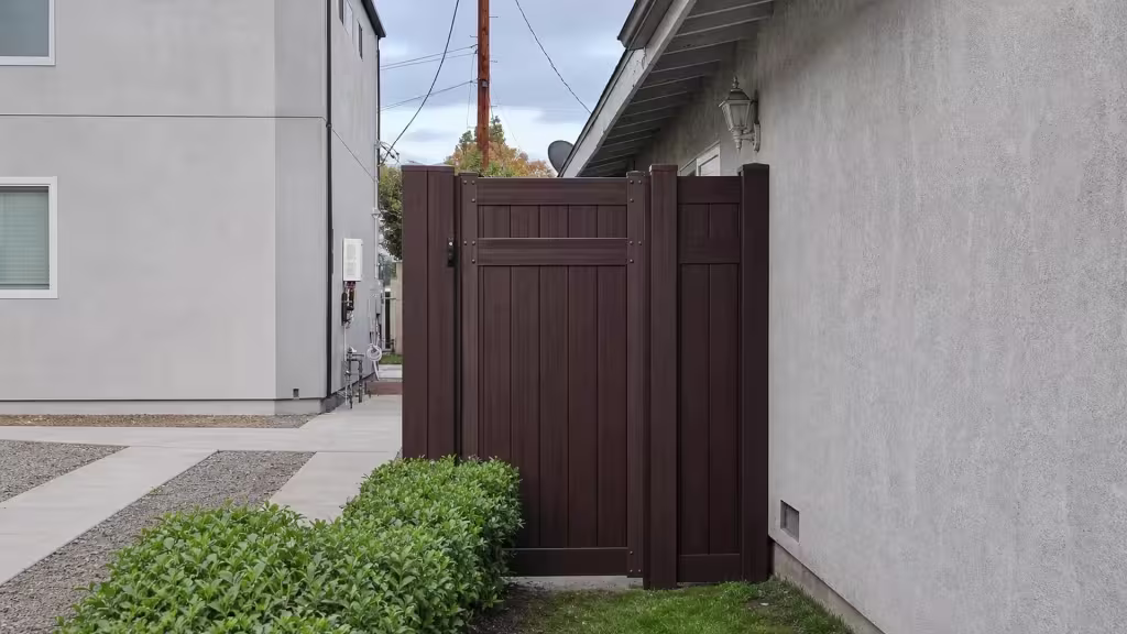 Dark Walnut vinyl side gate paired with a narrow fixed privacy panel beneath overhead utility wires