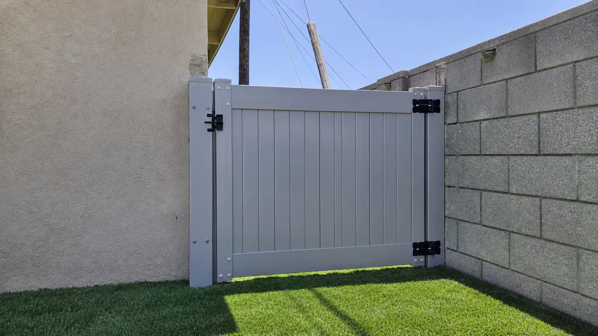 Slate Gray vinyl side gate closing a side yard beneath a utility pole and overhead wires