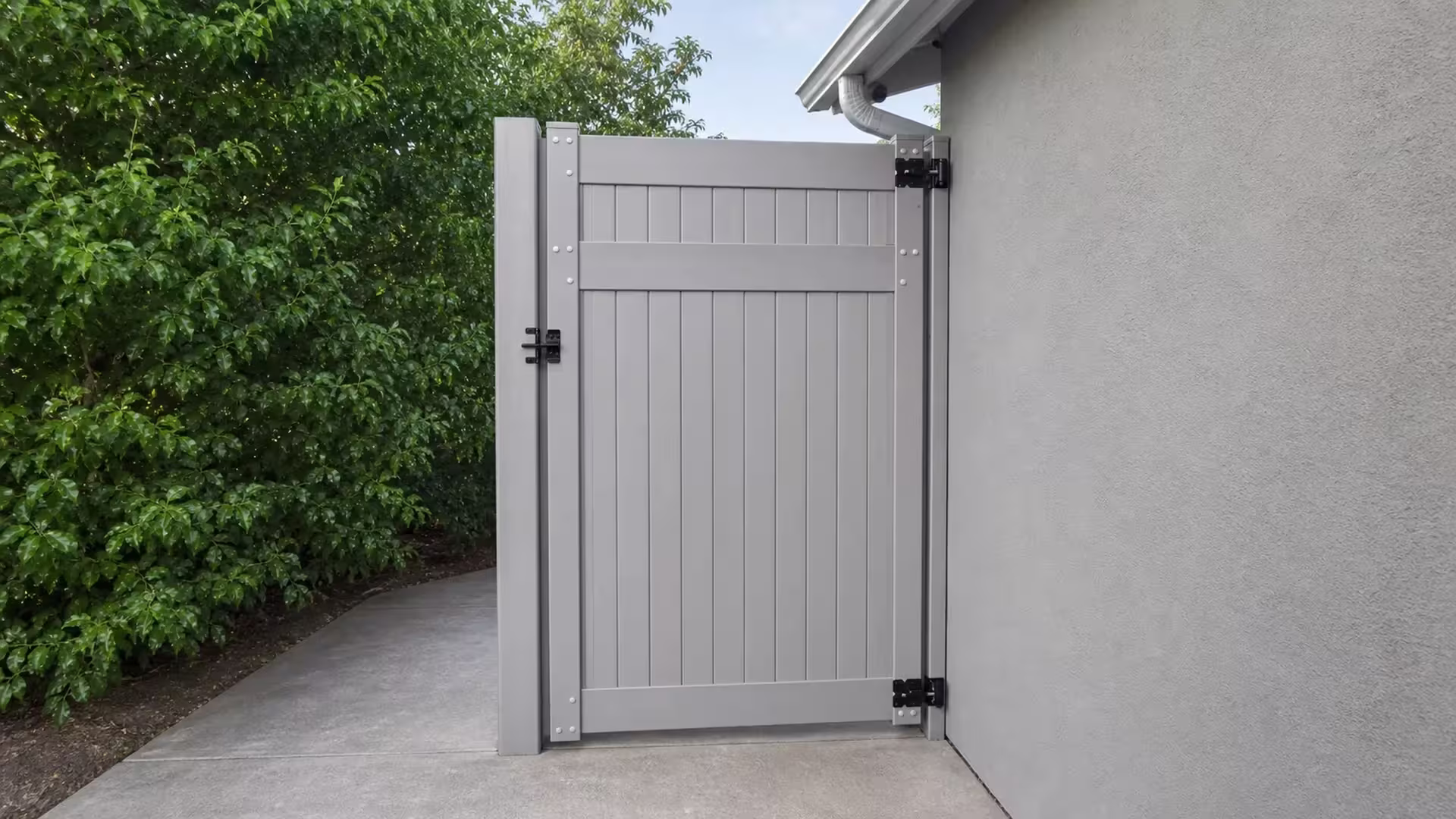 Slate Gray vinyl side gate hung between a storage structure and the light-gray stucco house wall
