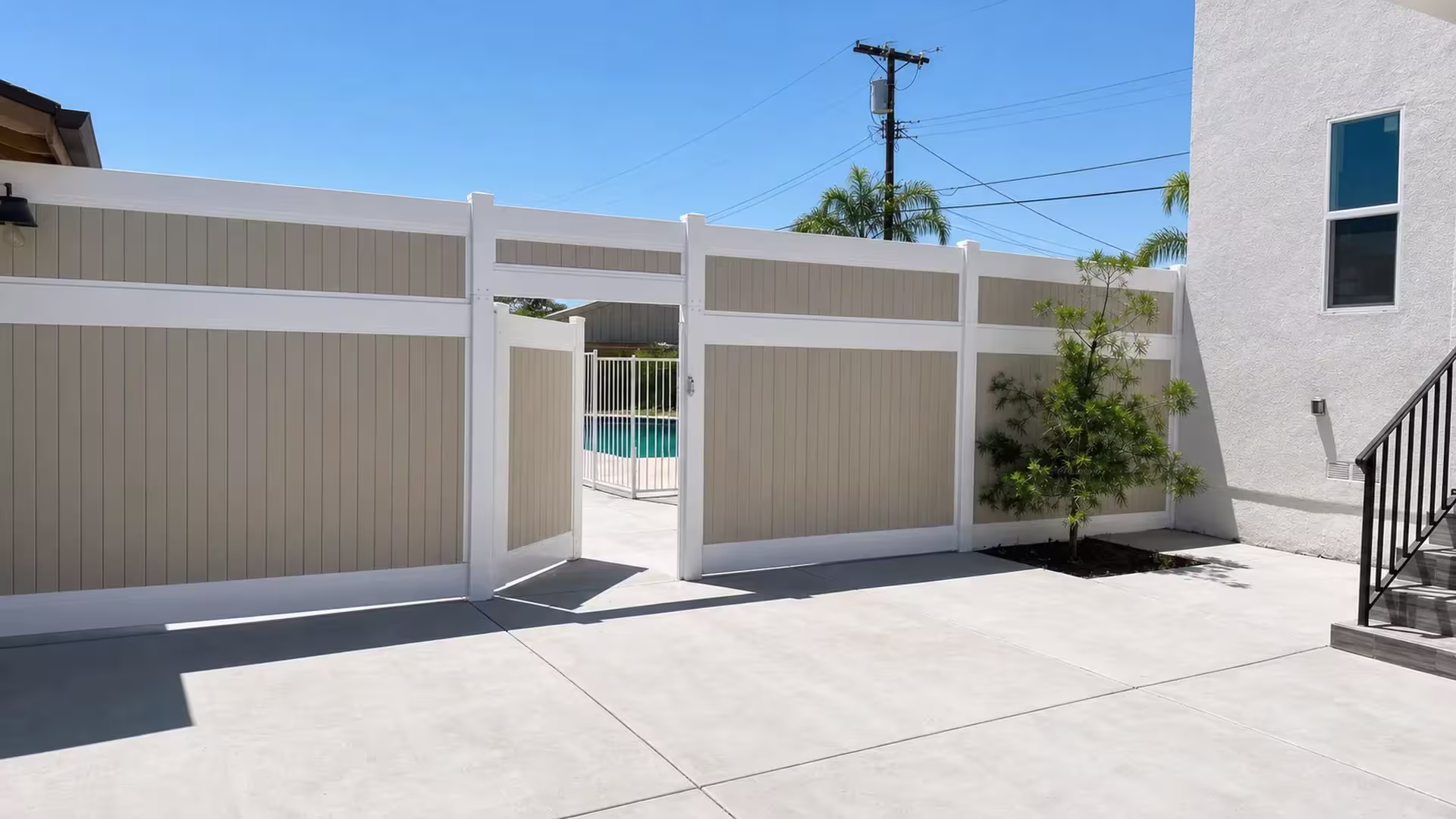 Tan vinyl side gate shown open within a continuous privacy fence run leading toward the house