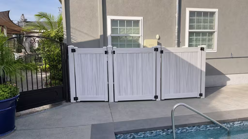 Weathered Aspen vinyl side gate positioned poolside near a stainless steel pool rail and a black metal gate