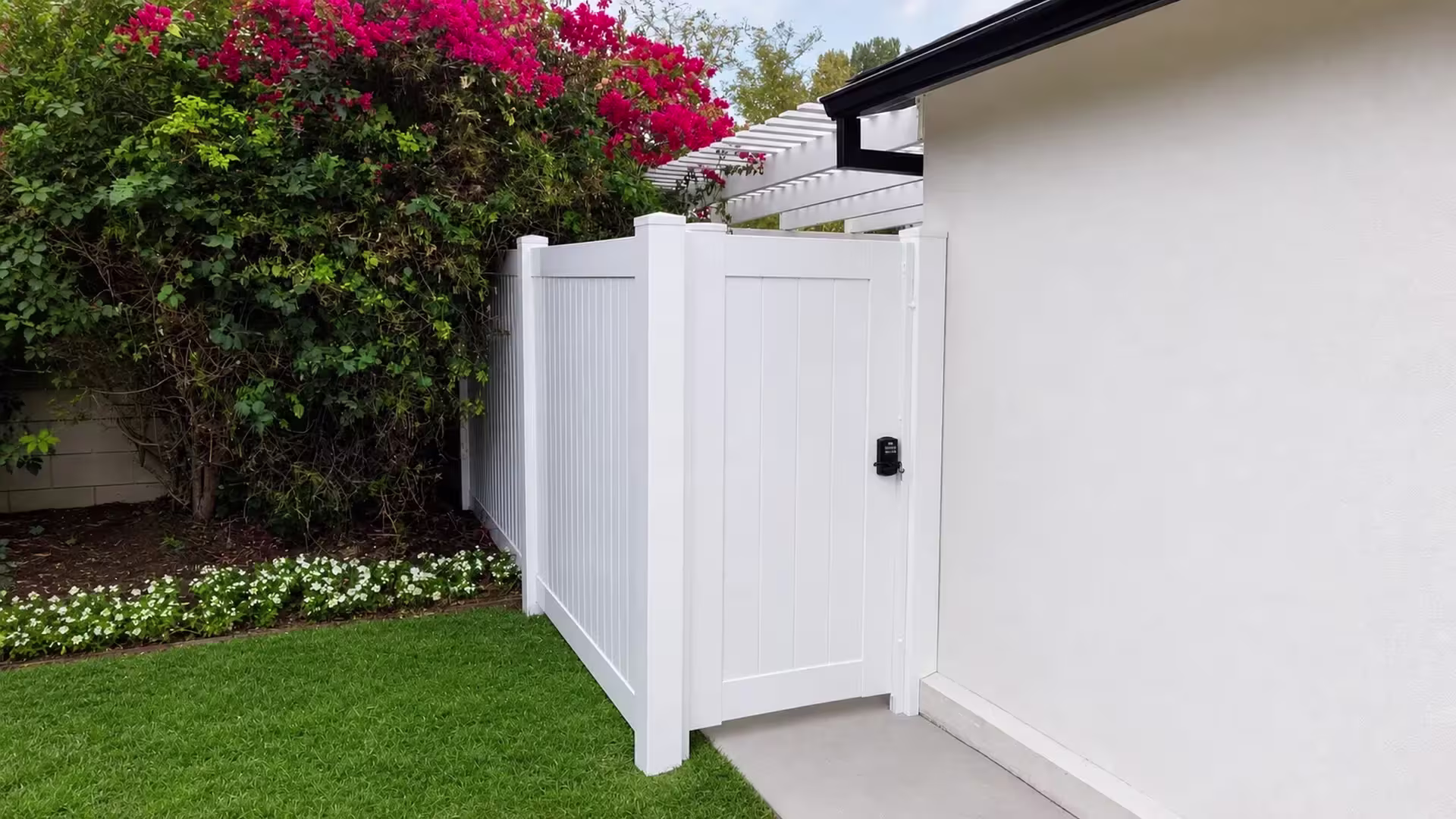 White vinyl side gate closed between a capped post and a narrow jamb fitted with a keypad latch