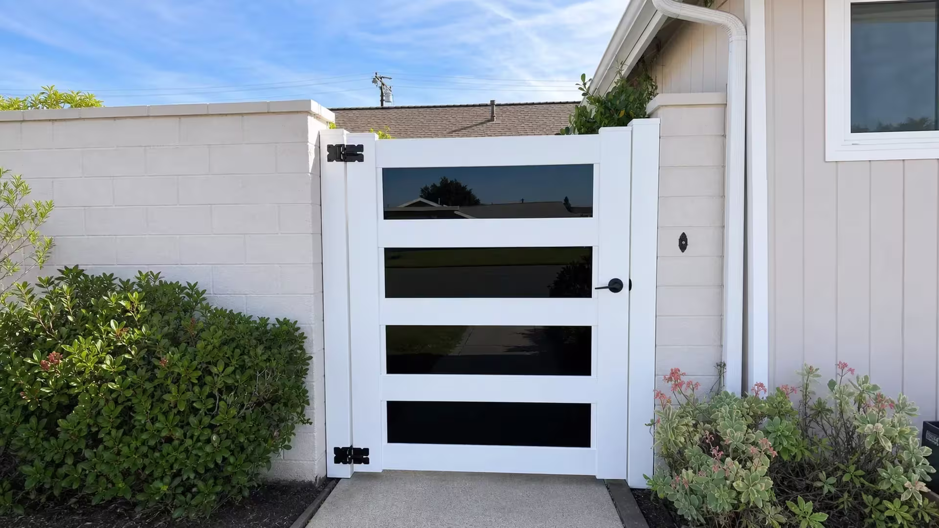 Four smoked acrylic panels stack vertically inside this White vinyl side gate frame
