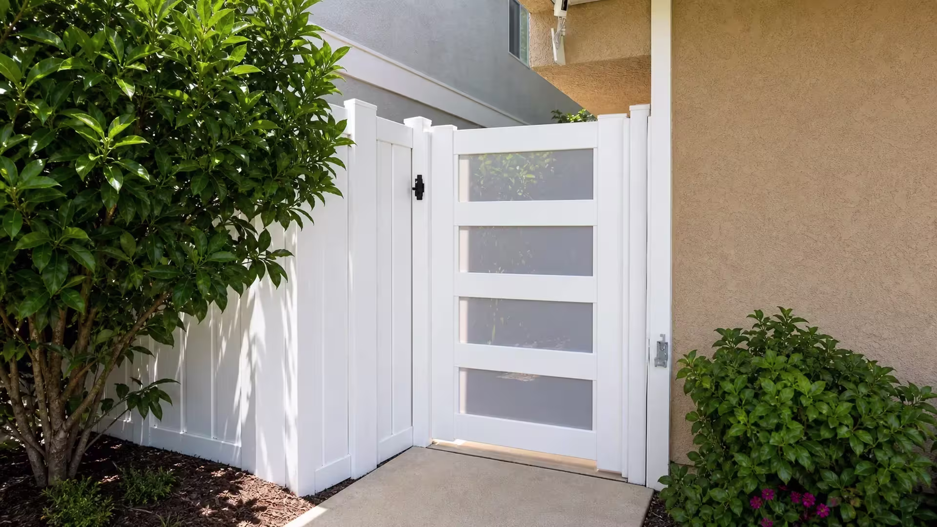 Four frosted acrylic openings fill this White vinyl side gate installed beside a beige stucco house wall