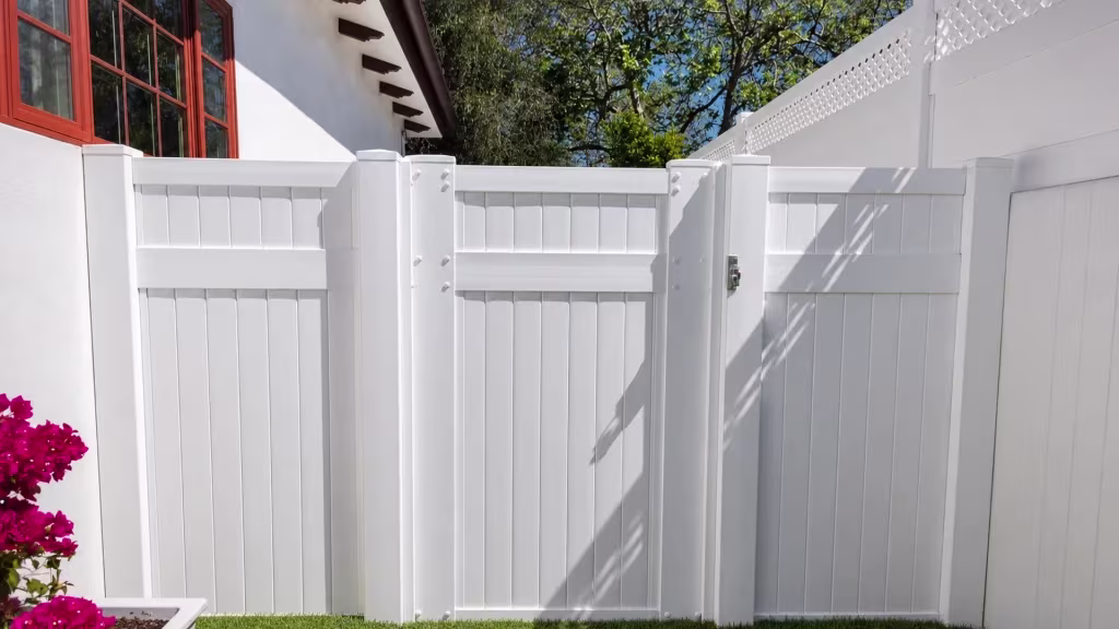 Exposed rafter tails top the roofline above this White vinyl side gate assembly and a small corner planter